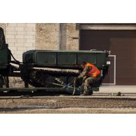 Un soldat fixe les chenilles d'un véhicule articulé chenillé (VAC) Bandvagn 206 à la plateforme d'un camion porteur polyvalent logistique (PPLOG) à Jõhvi, en Estonie.