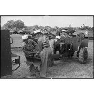 Des légionnaires de l'escadron antichars du 1er REC (régiment étranger de cavalerie) attèlent un canon de 57 mm M1 à un scout-car M3A1 à l'issue de la prise d'armes près de la forêt de la Mamora.