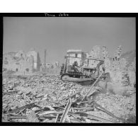 Un angledozer déblaie des gravats dans le village de Formia en ruine.<br>