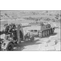 Un semi-chenillé Sd.kfz.7 s'apprête à tracter une pièce de 8,8 cm FlaK que les artilleurs viennent d'atteler.