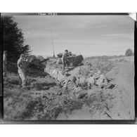 Un camion de dépannage tracte un chasseur de chars M10 (TD M10) embourbé d'une unité blindée de la 1re Armée.
