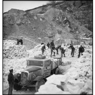 Des pionniers d'une unité de la 55e DI (division d'infanterie) chargent des pierres extraites d'une carrière dans la benne d'un camion Citroën type 45.