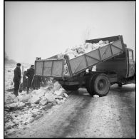 Des pionniers d'une unité de la 55e DI (division d'infanterie) déchargent des pierres extraites d'une carrière de la benne d'un camion Citroën type 45 pour la réfection d'une route.