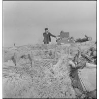 Un officier de marine donne des ordres de pointage par liaison radio aux servants d'un canon de 90 mm CA.