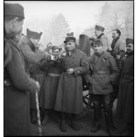 Un lieutenant de la 55e DI boit un café en compagnie de soldats près d'une cuisine roulante.