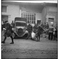 Plan général de soldats de la 55e DI qui portent des affaires près d'un camion .