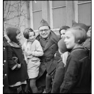 Portrait de Raymond Souplex, sergent au sein de la 55e DI, entouré d'enfants.