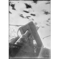 Un mortier d'artillerie de 280 mm Schneider est photographié en plan moyen de trois quarts dos et en contre-jour.