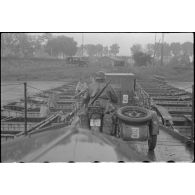 Des éléments d'une batterie d'artillerie 10,5 cm FH 18 traversent un pont flottant assemblé par le Génie allemand.