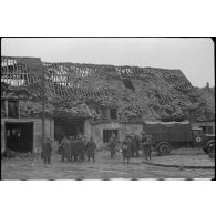 Des prisonniers français sont rassemblés devant un camion allemand.