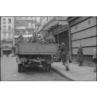 Dans une rue de Paris, un camion de la Luftwatfe chargé de soldats armés de fusil Mauser 98 k.