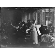 Paris, cantine du refuge du VIe arrondissement. La salle pendant le quatuor, Mme Herlerog chantant. [légende d'origine]