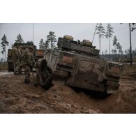 Des soldats britanniques déblaient la boue autour de la chenille d'un char Warrior embourbé en forêt de Tapa, en Estonie.