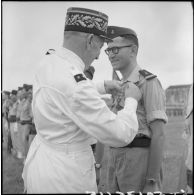 Remise de décoration à un lieutenant du BMI (bataillon de marche indochinois) par le général Marchand au cours d'une cérémonie sur le stade d'Haïduong.