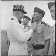 Remise de décoration à un sous-lieutenant du bataillon de marche indochinois (BMI) par le général Marchand au cours d'une cérémonie sur le stade d'Haïduong.
