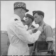 Remise de décoration à un soldat du bataillon de marche indochinois (BMI) par le général Marchand au cours d'une cérémonie sur le stade d'Haïduong.