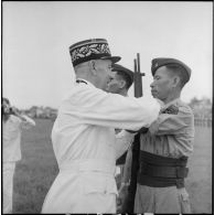 Remise de décoration à un caporal du bataillon de marche indochinois (BMI) par le général Marchand au cours d'une cérémonie sur le stade d'Haïduong.