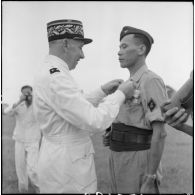 Remise de décoration à un soldat du bataillon de marche indochinois (BMI) par le général Marchand au cours d'une cérémonie sur le stade d'Haïduong.