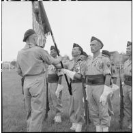Remise du drapeau de l'ancien 1er RTT par le capitaine Bigeard, commandant le BMI (bataillon de marche indochinois), à sa nouvelle garde au cours d'une cérémonie sur le stade d'Haïduong.