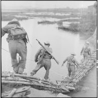 Passage d'un pont en bambou par les premiers éléments du groupement "Sizaire" armés de FM M24/29 et MAS 36.