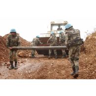 Les sapeurs du 13e RG (régiment du Génie) transportent une roquette non explosée vers la benne d'une pelleteuse en vue de sa destruction.