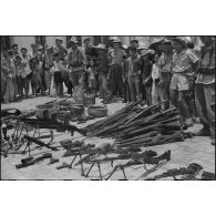 Les armes récupérées à l'ennemi sont exposées en faisceau sur la place de l'église de Ke Sat.
