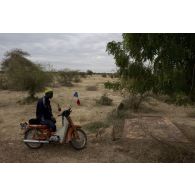 Un habitant arbore les drapeaux français et malien sur son mobylette à l'arrivée des troupes franco-maliennes à Tombouctou, au Mali.