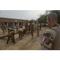 Un instructeur du Service de santé des armées (SSA) encadre le montage d'un module sanitaire par des stagiaires burkinabè à Dori, au Burkina Faso.