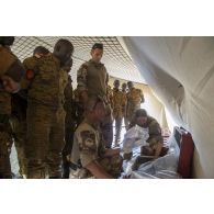 Des instructeurs du Service de santé des armées (SSA) encadrent l'installation de l'équipement médical à l'intérieur d'un module sanitaire par des stagiaires burkinabè à Dori, au Burkina Faso.