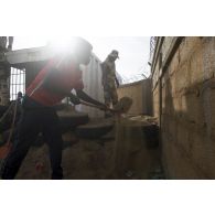 Un stagiaire burkinabè consolide le mur d'enceinte de sa caserne sous le regard d'un instructeur à Dori, au Burkina Faso.