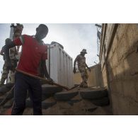 Un stagiaire burkinabè consolide le mur d'enceinte de sa caserne sous le regard d'un instructeur à Dori, au Burkina Faso.