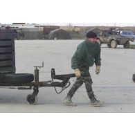 Sur l'aéroport de Mazar e Charif, un personnel du DTIA (détachement de transit interarmées) tire un groupe électrogène sur remorque pour son chargement dans un avion de transport à destination de Kaboul.