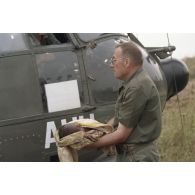 Le médecin en chef Auclaire commandant l'elément médical militaire d'intervention rapide (EMMIR) porte un bébé évacué avec sa mère devant un hélicoptère de transport Puma à Cyangugu, lors de l'évacuation sanitaire de blessés du camp de réfugiés de Kibeho.