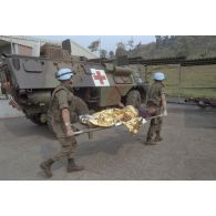 Dans une clinique près de Goma, débarquement d'une femme enceinte protégée par une couverture de survie sur un brancard depuis un véhicule de l'avant blindé sanitaire (VABSAN) du 1er régiment médical (1er RMed) de Metz par des casques bleus.