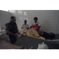 Dans une clinique près de Goma, prise en charge d'une femme enceinte protégée par une couverture de survie évacuée par des casques bleus sur un brancard.