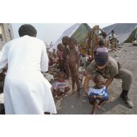 Jeunes enfants regroupés, surveillés et soignés avec l'aide de personnels militaires et de civils dans un camp de réfugiés.
