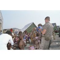 Jeunes enfants regroupés, surveillés et soignés avec l'aide de personnels militaires et de civils dans un camp de réfugiés.