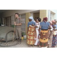 Filtrage des consultations à l'entrée de l'hôpital Saint-François à Cyangugu par un militaire qui se tient à côté d'un bac souple.