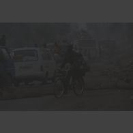 Un militaire zaïrois à vélo longe les cadavres abandonnés rangés au bord de la route au poste-frontière de Goma-Gisenyi.