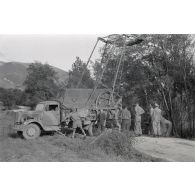 Dépannage d'une voiture par une grue Kfz-Aufsetzkran 3t installée sur un camion Opel Blitz.