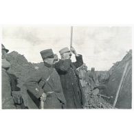 [Le général Fayolle, accompagné du commandant Gardes observe les tranchées avec un périscope].
