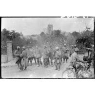 [Un groupe de soldats et de prisonniers devant un village].