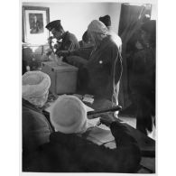 Un soldat français et un Algérien dans un bureau de vote en train de voter. [légende d'origine]<br>