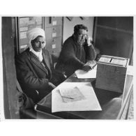 Personnel administratif assis devant une urne servant au vote. [légende d'origine]<br>