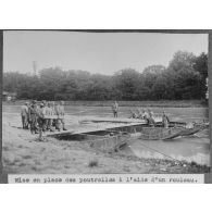 Mise en place des poutrelles à l'aide d'un rouleau. [légende d'origine]