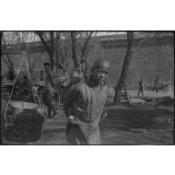 [Un jeune garçon porte un nourrisson sur son dos dans une rue de Pékin].