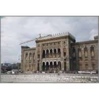 La bibliothèque de Sarajevo, incendiée le 25 août 1992 (elle comptait alors un million de volumes). Ici en reconstruction. [légende d'origine]