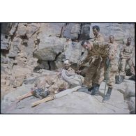 Formation des aides moniteurs commando et des élèves officiers de l'école militaire interarmes d'Atar à l'escalade et au rappel, aux techniques de cordes et d'assurance, au franchissement de fortune, au brancardage dans les falaises de l'Oued Illïj, région d'Atar et d'Azougui. Température d'exercice avoisisant les 40° en raison du rayonnement sur les parois rocheuses, 300 élèves et 10 aides moniteurs ont été formés pendant cette période. [légende d'origine]<br>