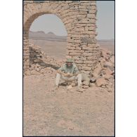 Le major Rémi Labbée pose sous l'arche des ruines du décor de cinéma réalisé pour le film "Fort Saganne". [légende d'origine]<br>