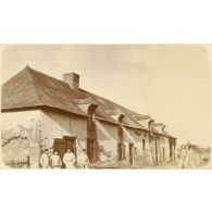 [Portrait de groupe de 4 soldats en tenue de travail devant une ferme]